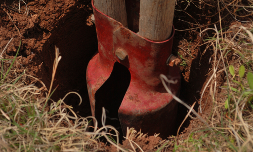 post hole diggers digging a hole in the ground